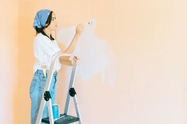 Interior painting in Rochester: painter on a stepladder rolling a wall
